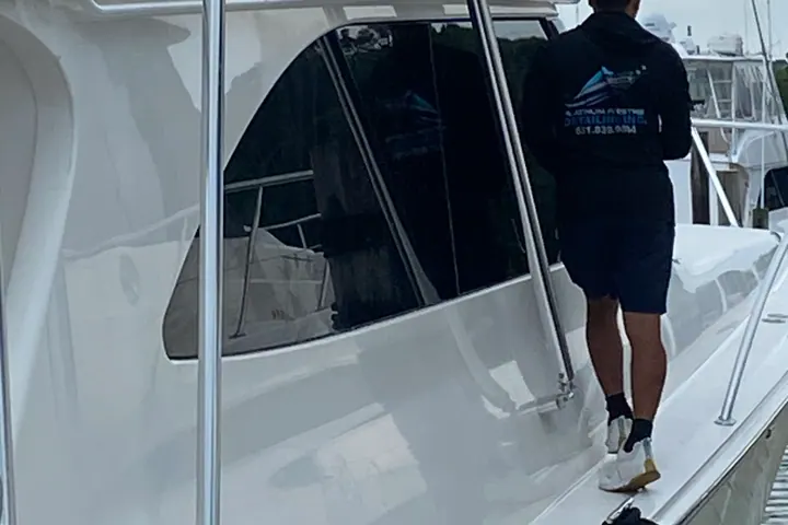 A Platinum Prestige crew member in a branded shirt stepping aboard a sport fisherman at the dock at the end of a detail