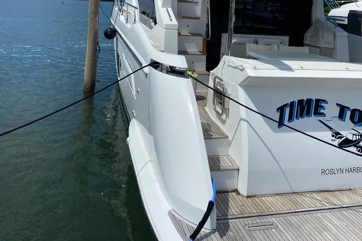 A large motor yacht lying stern-to at a Sag Harbor dock with the bay opening out beyond her transom