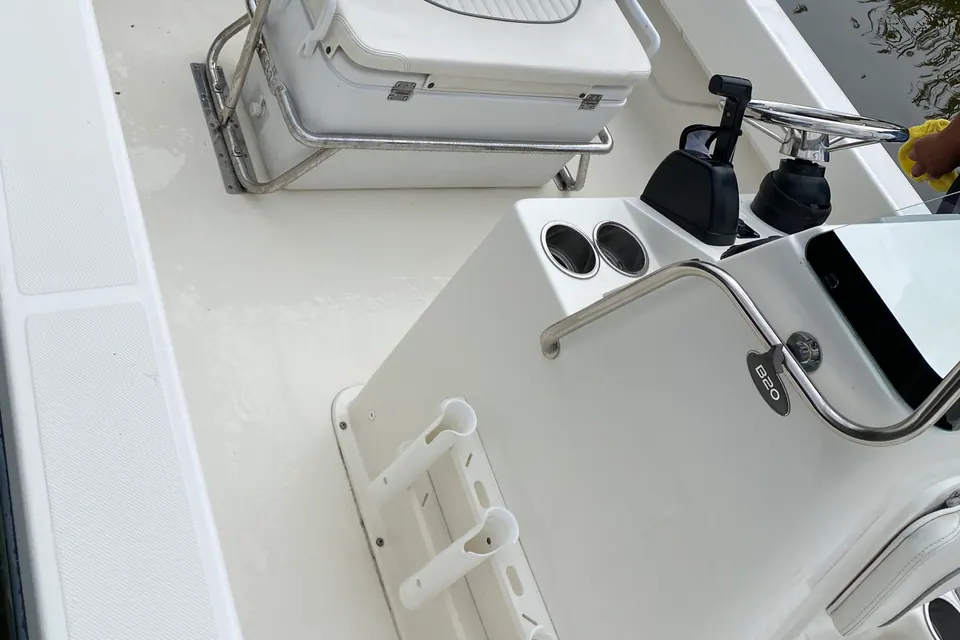 The same centre console cockpit after detailing, the non-skid deck and gelcoat scrubbed back to bright white while a detailer wipes down the console