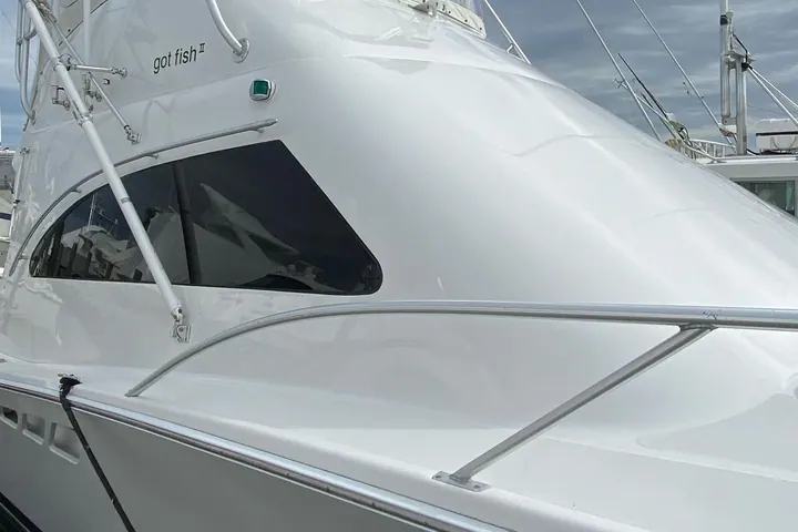 The glossy white superstructure of a convertible sport fisherman after a full detail, marina masts behind it