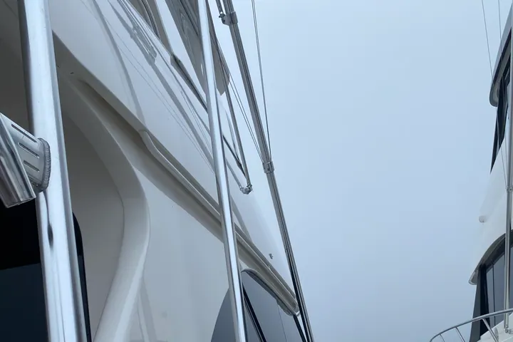 The white flybridge and hardtop of a sport fishing boat, gelcoat polished until it reflects the sky