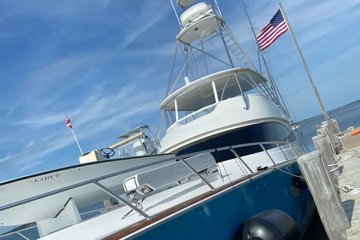 A classic blue-hulled convertible sport fisherman flying the American flag at her slip, topsides waxed to a deep shine