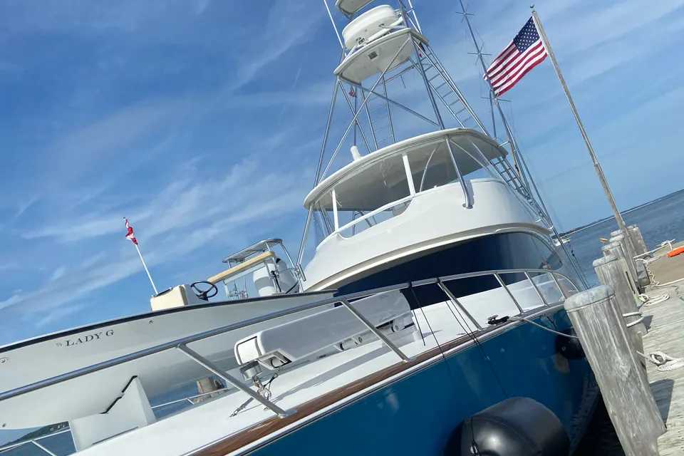 A classic blue-hulled convertible sport fisherman flying the American flag at her slip, topsides waxed to a deep shine