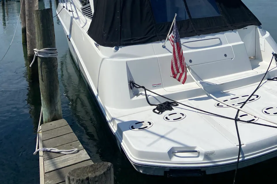 A white flybridge motor yacht at her slip with the American flag flying, hull and superstructure detailed bow to stern