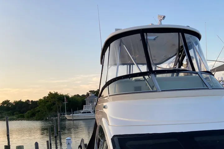 A detailed motor yacht at dusk in a quiet Long Island marina, canvas zipped and gelcoat still shining in the last light