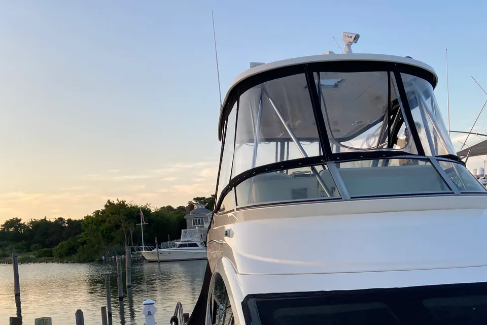 A detailed motor yacht at dusk in a quiet Long Island marina, canvas zipped and gelcoat still shining in the last light