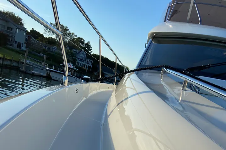 The sweeping white bow of a sport cruiser polished to a wet-look gloss, sky mirrored in the gelcoat