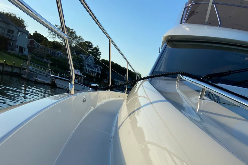 The sweeping white bow of a sport cruiser polished to a wet-look gloss, sky mirrored in the gelcoat