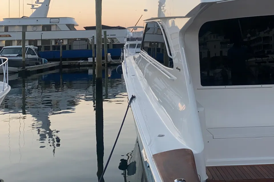 Golden hour at the marina, looking across the varnished teak covering board and helm of a freshly detailed sport fisherman