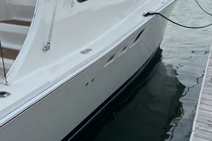 A white express cruiser at her slip after a full exterior detail, hull sides free of waterline stains and streaking