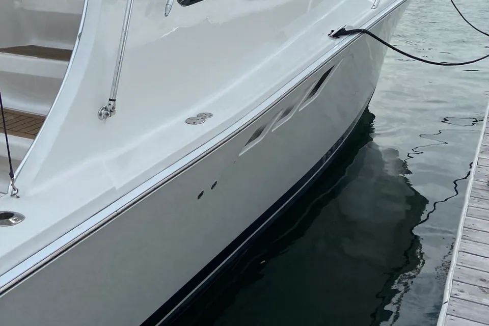 A white express cruiser at her slip after a full exterior detail, hull sides free of waterline stains and streaking