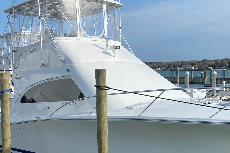 A detailed white convertible sport fisherman alongside a piling on a calm summer morning